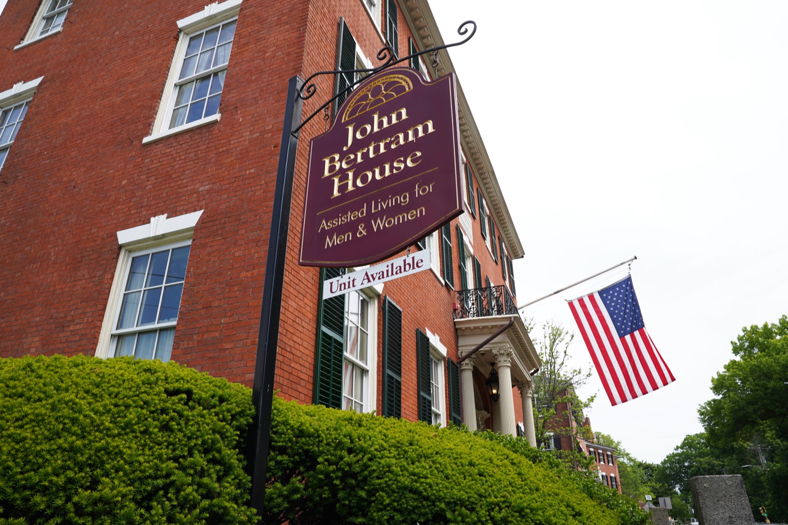 John Bertram House sign and historic brick facade with American flag at the Salem community